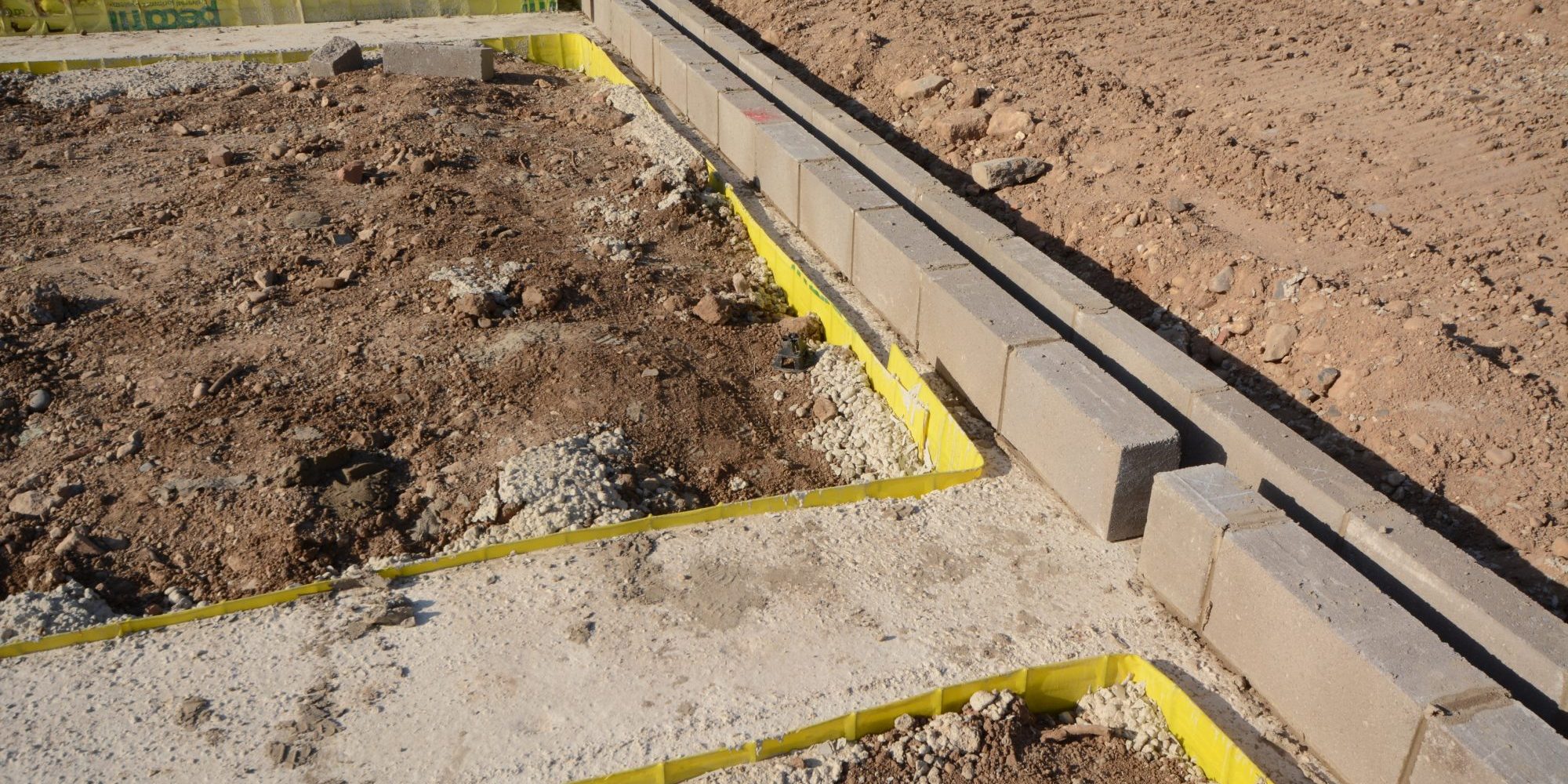 Groundwork and steel re-inforcement for concrete base on building construction site where new homes are being built showing construction methods.